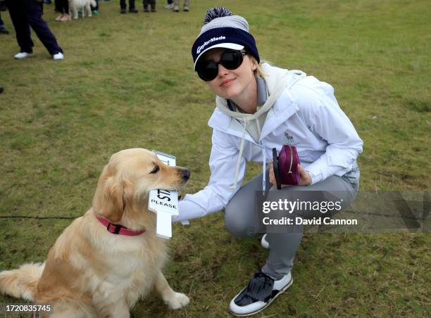 Kathryn Newton the American film actress meets a marshal's dog who is holding a 'quiet please' sign on the ninth hole during Day Two of the Alfred...