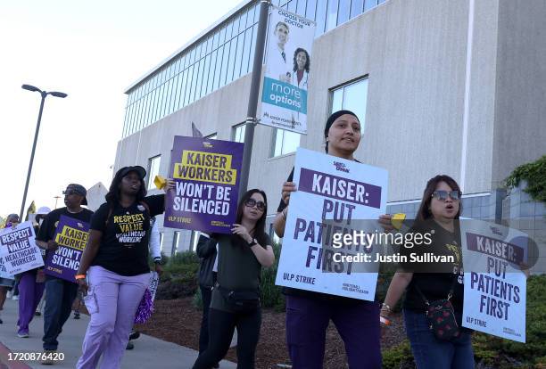 Striking Kaiser Permanente workers hold signs as they march in front of the Kaiser Permanente Vallejo Medical Center on October 06, 2023 in Vallejo,...