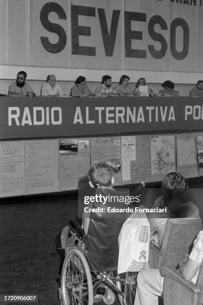 View, over audience members, of participants in an unspecified panel discussion, Seveso, Italy, July 10, 1977. The photo was taken on the one year...
