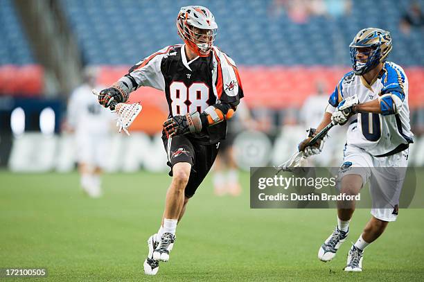 Zack Greer of the Denver Outlaws runs with the ball as Jake Tripucka of the Charlotte Hounds defends during a Major League Lacrosse game at Sports...