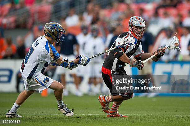 Justin Pennington of the Denver Outlaws drives and is covered by Peet Poillon of the Charlotte Hounds during a Major League Lacrosse game at Sports...