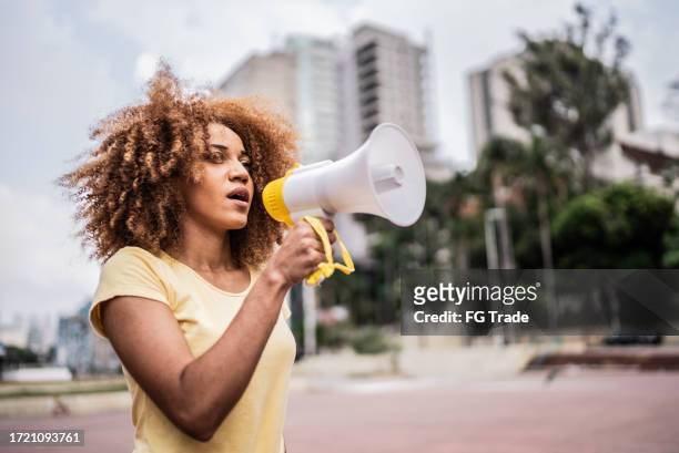 young woman talking in a megaphone at city street - human rights day stock pictures, royalty-free photos & images