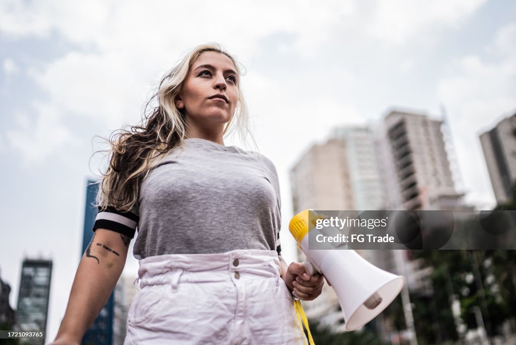 Young woman holding a megaphone at city street