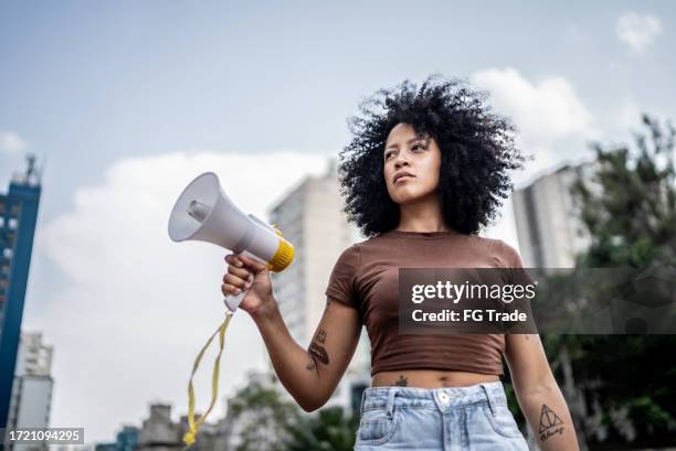 young woman holding a megaphone at city street - parade stock pictures, royalty-free photos & images