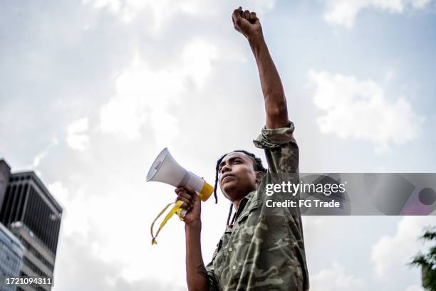 joven hablando en un megáfono en la calle de la ciudad - manifestante fotografías e imágenes de stock