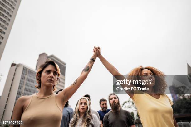 women holding hands during a protest at city street - social justice concept stock pictures, royalty-free photos & images