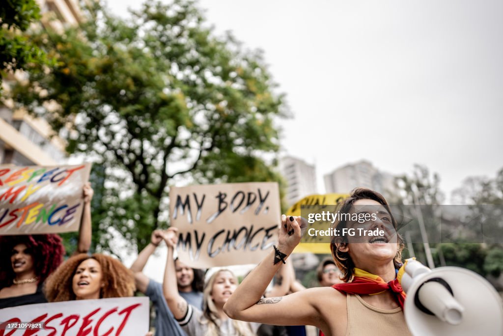 Young woman talking in a megaphone during a protest in the street
