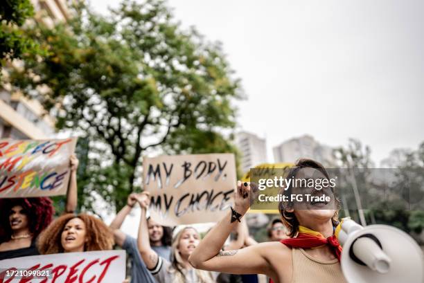 giovane donna che parla in un megafono durante una protesta in strada - uguaglianza di genere foto e immagini stock