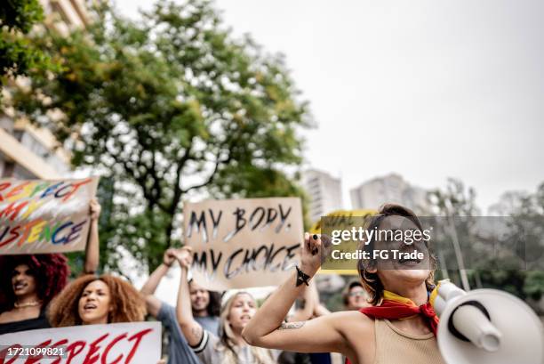 young woman talking in a megaphone during a protest in the street - women's rights stock pictures, royalty-free photos & images