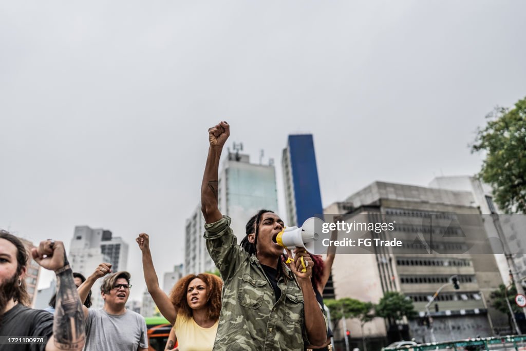 Young man talking in a megaphone during a protest in the street