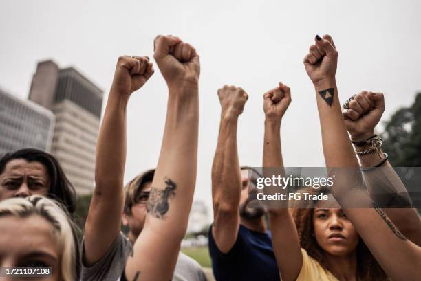 people with fist up during a protest at city street - walkout protest stock pictures, royalty-free photos & images