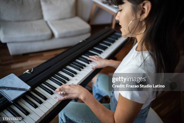 young woman playing synthesizer at home - pianist stock pictures, royalty-free photos & images