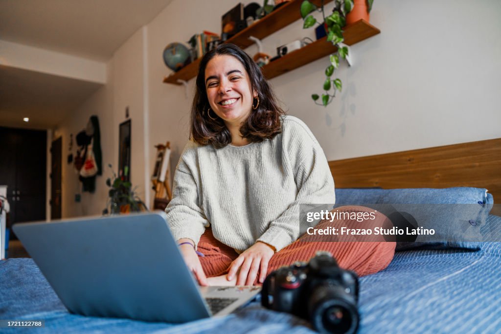 Retrato de uma jovem mulher do fotógrafo usando o laptop para editar fotos em casa