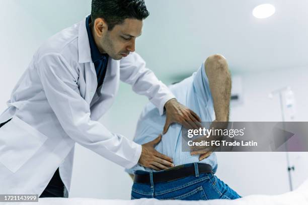 doctor examining a patient in pain at the hospital - scoliosis stock pictures, royalty-free photos & images