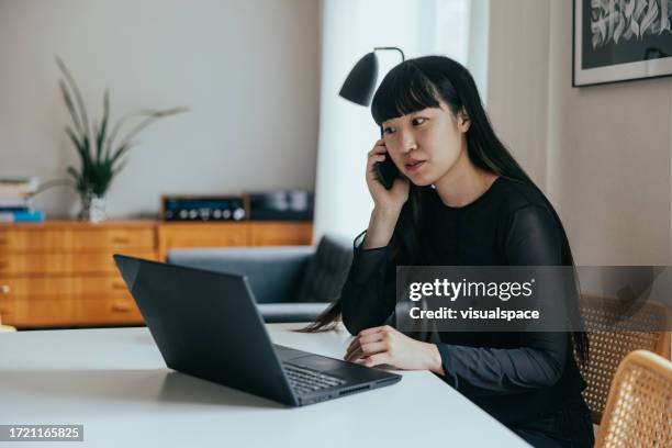 japanese woman using laptop while on a phone call - scam victim stock pictures, royalty-free photos & images