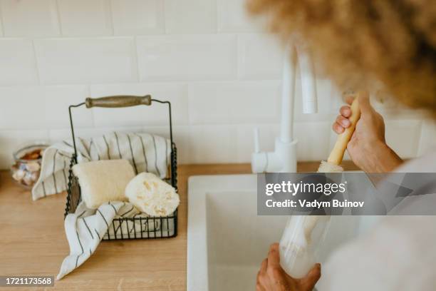 young woman washing reusable glass bottle with natural brush - house cleaning stock pictures, royalty-free photos & images