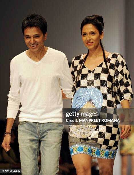 Indian designer Rohit Mittal acknowledges the applause as he walks the ramp with a model at his show during the Wills India Fashion Week Spring...