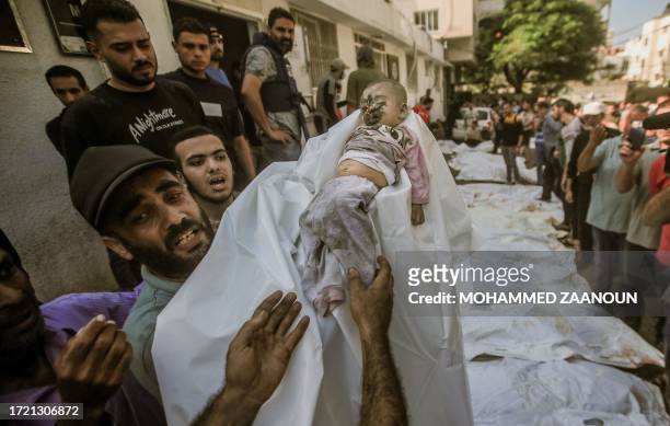 Gaza, Palestine. People wait outside Shifa Hospital to carry away the bodies of Palestinians and babies who lost their lives in Israeli airstrikes as...