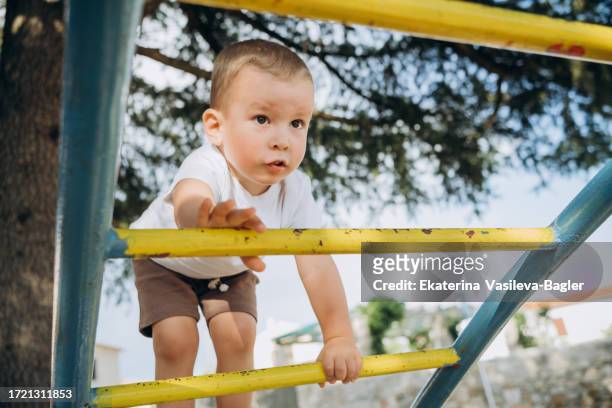child climbs up the stairs on the playground training agility and balance - baby first steps stock pictures, royalty-free photos & images