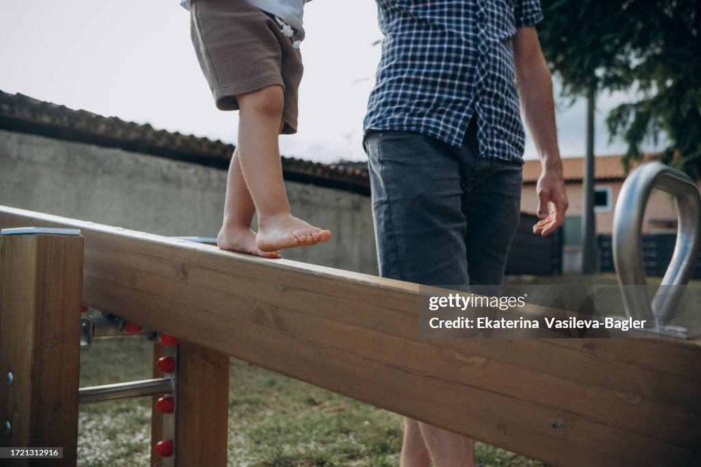 Man helps a child keep his balance on the playground