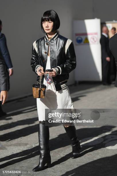 Bae Doona wears a black and white leather teddy jacket, a white knee long dress with lace borders, a brown monogram leather LV bag, knee high leather...