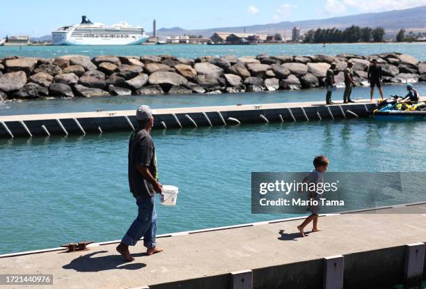 People walk on a dock near the Norwegian Spirit cruise ship, moored at Kahului Harbor in Maui during a tourism visit, on October 06, 2023 in Kahului,...