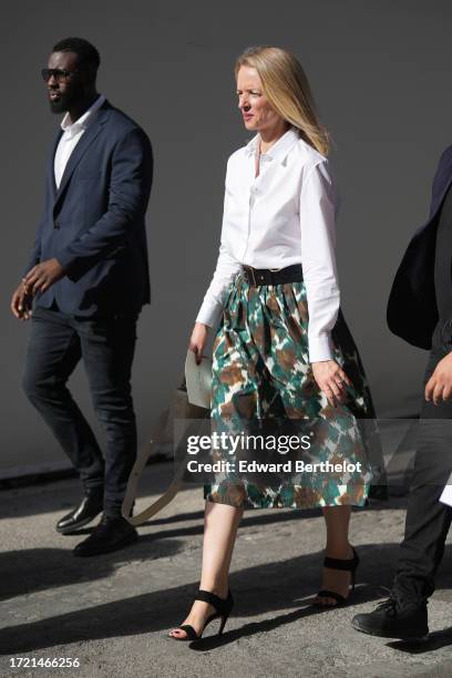 Delphine Arnault wears a white shirt, a green and brown midi floral print skirt, high heels shoes outside Louis Vuitton , during the Womenswear...