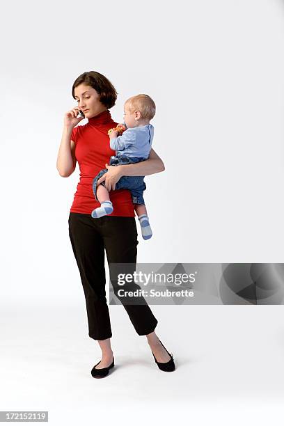 woman on mobile phone holding baby - baby sitting studio stock pictures, royalty-free photos & images