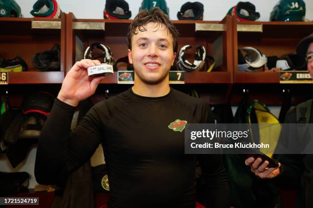 Brock Faber of the Minnesota Wild holds up a puck after scoring his first career NHL goal during the game against the Florida Panthers at the Xcel...