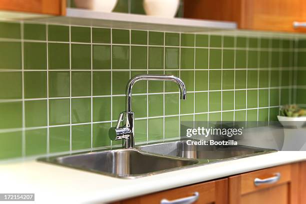 close-up of kitchen sink with green splash board - daktegel stockfoto's en -beelden