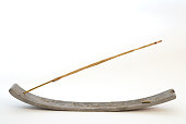 An incense stick burning on a curved plank