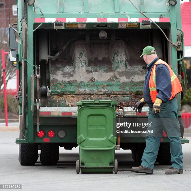 a garbage man dumping a bin into the garbage truck - vuilnisman stockfoto's en -beelden