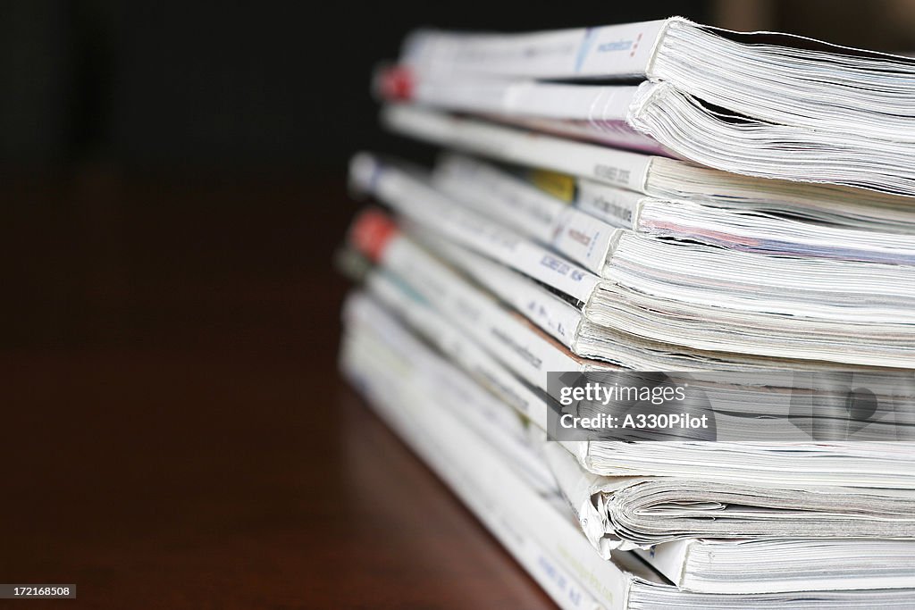 Stack of magazines over a wooden desk