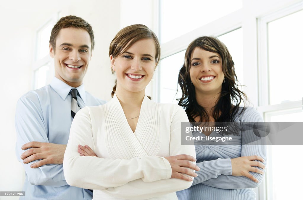Two women and one man smiling with arms crossed