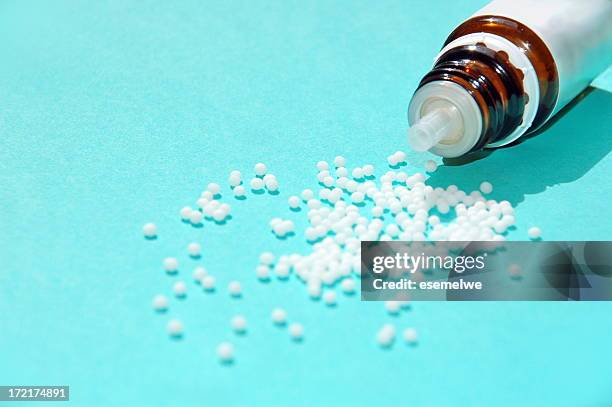 small white pearls and a bottle on a blue background - homeopathie stockfoto's en -beelden
