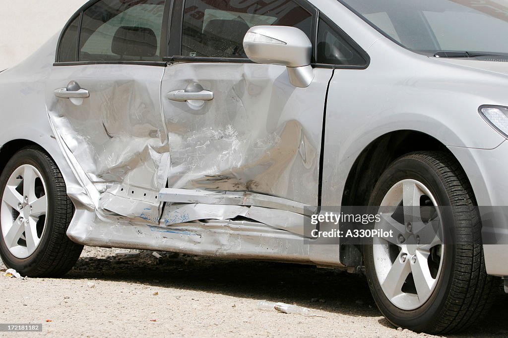 Silver car with a large dent in the side, ruining two doors