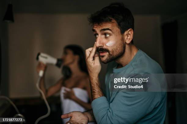 momento intimo del bagno catturato mentre una coppia multiculturale condivide la loro routine mattutina - trattamento per la pelle foto e immagini stock