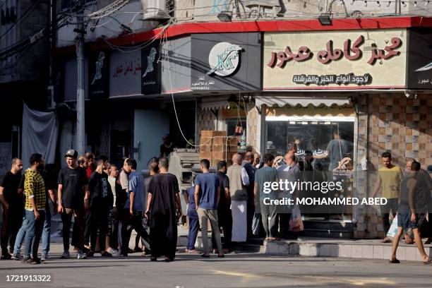 Palestinians line up outside a shop in Gaza City after Israeli air strikes, on October 13, 2023. Israel has called for the immediate relocation of...