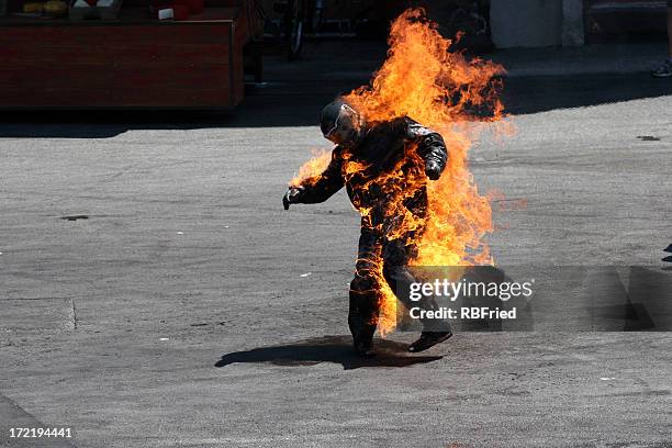 man in a protective suit wrapped in flames - stunt stock pictures, royalty-free photos & images