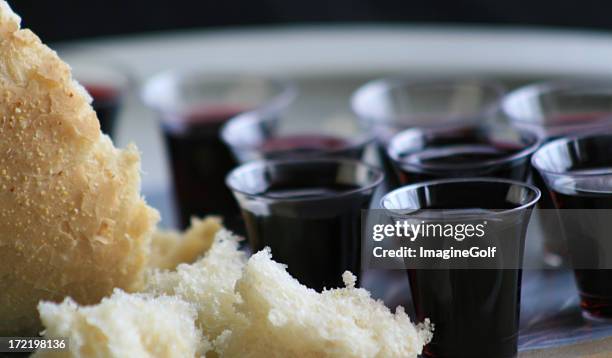 small wine cups and broken bread for communion - heilige communie stockfoto's en -beelden