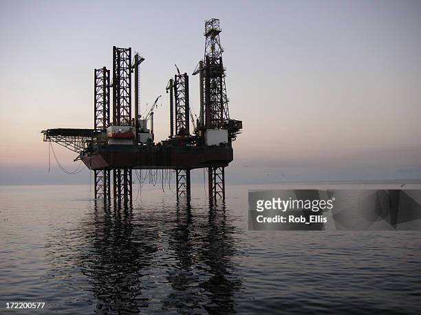 a distant shot of an oil rig at dusk - gulf of mexico oil rig stockfoto's en -beelden