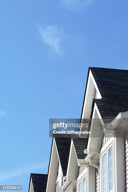 row of roofs and eaves of homes with blue sky - rooftop stock pictures, royalty-free photos & images