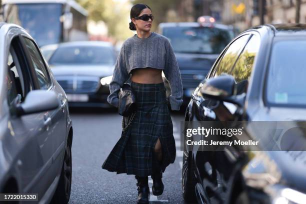 Fashion Week guest is seen wearing black chades, yellow gold earrings, a grey cropped Miu Miu shirt, a black Chanel bag and a green checked long...