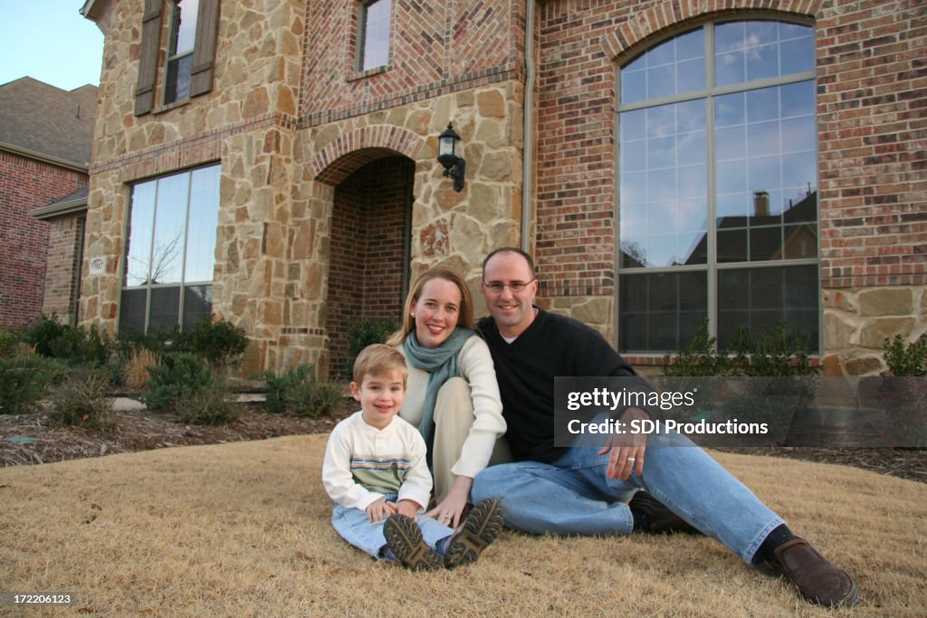Family Sitting In Front Of Their New House Purchased