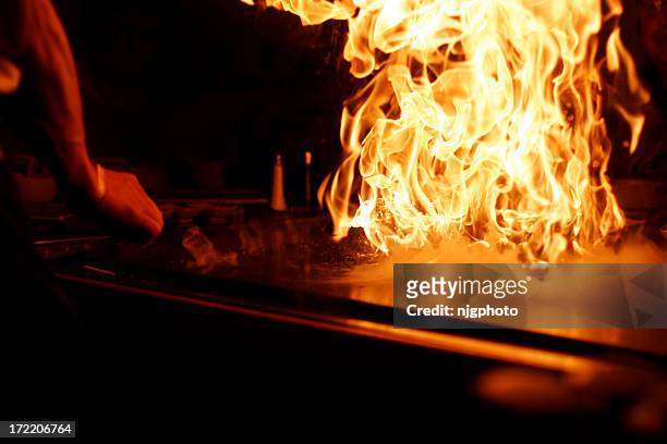 a person cooking with a high fire flame - teppanyaki stock pictures, royalty-free photos & images
