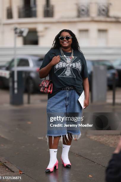 Gabriella Karefa Johnson is seen outside Chanel show wearing black and white Balenciaga sunnies, silver necklaces, grey vintage band t-shirt, long...