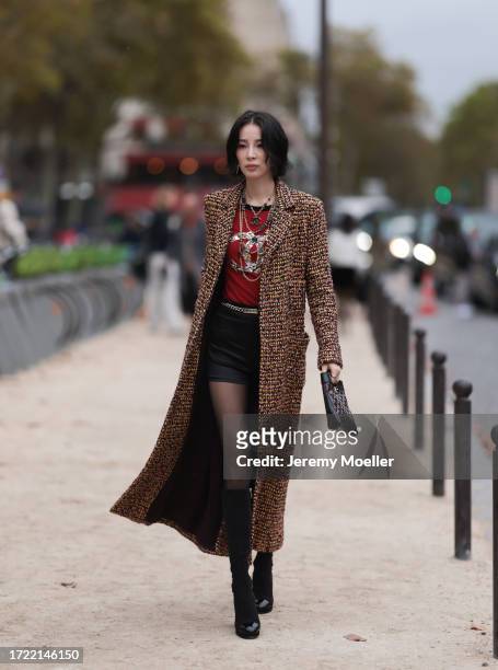 Irene Kim is seen outside Chanel show wearing gold Chanel necklaces, yellowish tweed Chanel coat, black leather shorts, golden Chanel belt, black...