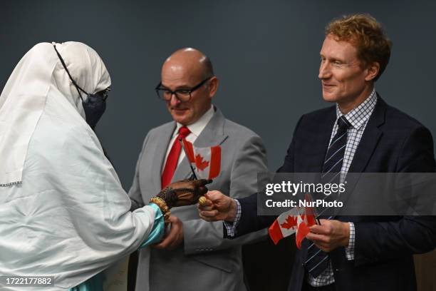 Marc Miller , Minister of Immigration, Refugees and Citizenship, hands small Canadian flag to one of 53 new Canadian citizens representing 22 diverse...