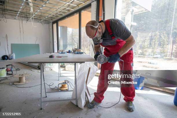 worker with red clothes cutting tile - slijptol stockfoto's en -beelden