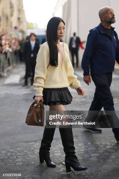 Taeyeon wears a pastel yellow low-neck v-neck pullover, a black ruffled / pleated mini skirt, a brown monogram leather bag from Vuitton, knee high...